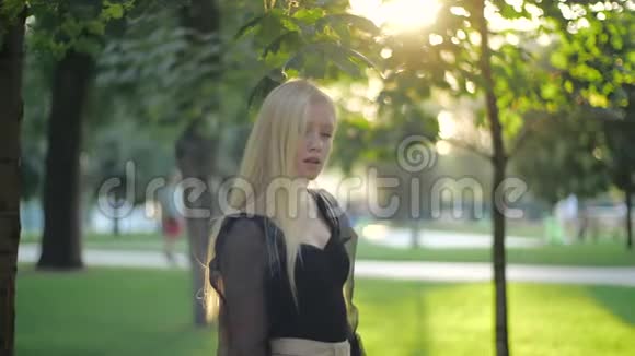 美丽的白种人女孩时装模特独自在公园里转过身来微笑着看着相机散步挺直身体视频的预览图