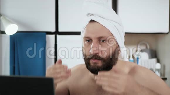 男人在做面部按摩一个穿着毛巾在浴室里长着迷人胡须的男人正在做手按摩视频的预览图