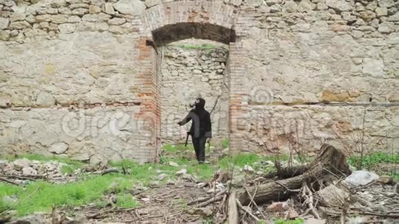 一个穿着黑色衣服和防毒面具的流浪男人穿过一座废弃的建筑后世界末日视频的预览图