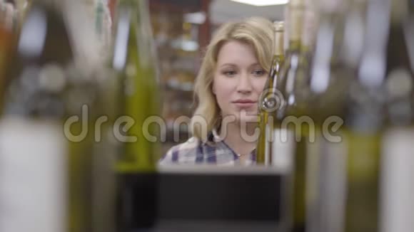 一个积极的白人金发女人出现在一瓶白葡萄酒之间微笑的女士喝了一杯饮料和视频的预览图