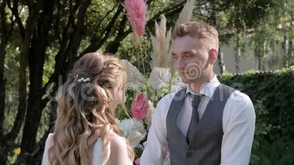 一个女孩和一个男人在一个花拱的背景上互相握住对方手视频的预览图