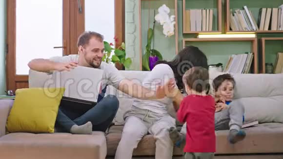 在客厅里一对年轻夫妇和他们的孩子一起度过美好的时光微笑着玩着可爱的游戏呆在家里视频的预览图