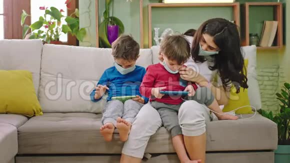 在家里的沙发上隔离妈妈和孩子们一起玩智能手机游戏视频的预览图