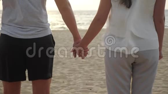 快乐的女人和男人的身影携手在空洋滩上视频的预览图
