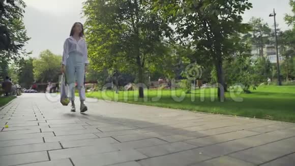 美丽的年轻女子拿着带蔬菜的棉网购物袋在夏季公园散步视频的预览图