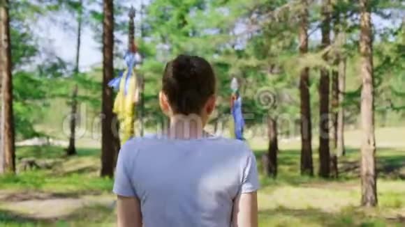 一个女孩在森林里用彩带穿过两根柱子后景4K视频的预览图