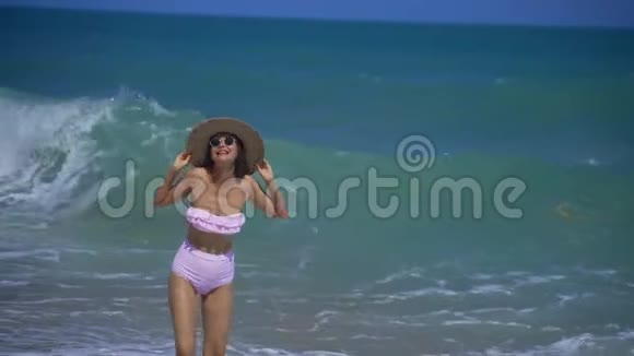 一个穿着稻草的漂亮女孩欢快地笑着从沙滩上的波浪中跑掉了视频的预览图