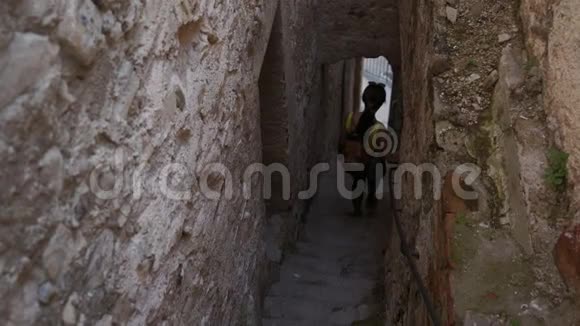 年轻的女游客背着背包走下楼梯在狭窄的堡垒隧道里视频的预览图