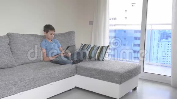 在家学习冠状病毒检疫期间的远程学习有平板电脑的男孩坐在房间里兄弟视频的预览图