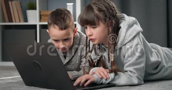 两个微笑的孩子在笔记本电脑上玩游戏视频的预览图