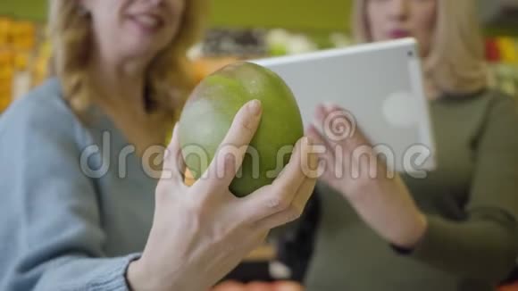 特写女性白种人手托柚作为模糊妇女使用平板电脑的背景自信积极视频的预览图