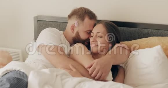 快乐的男人和女人在床上玩得很开心微笑的丈夫在他美丽的妻子耳边低语视频的预览图