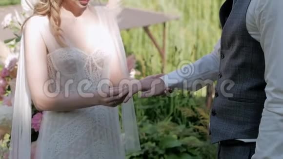 婚礼上的新娘在拱门的背景下给未婚夫戴上戒指视频的预览图