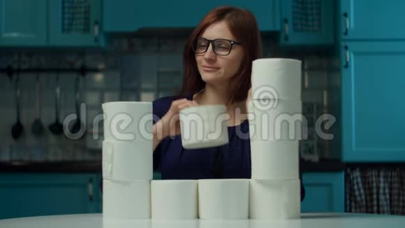 30岁的年轻女性戴着眼镜做着卫生纸坐在厨房里的塔楼在冠状病毒COVID19期间视频的预览图