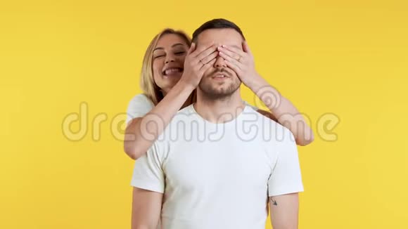 猜猜是谁给他一个惊喜美丽的年轻女子用黄色背景遮住男友的眼睛视频的预览图