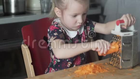 一个小女孩在厨房的家里给一个烤架上擦胡萝卜视频的预览图
