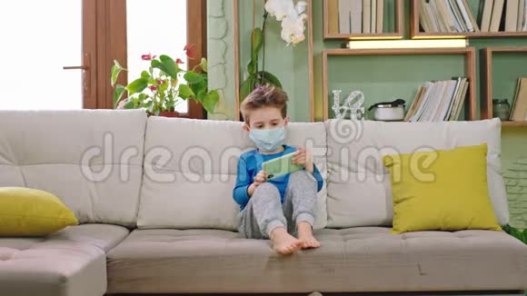 在镜头前呆在家里一个男孩在用智能手机玩隔离游戏时花时间视频的预览图