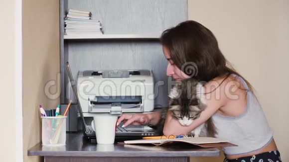 一个年轻的白种人女孩正坐在工作场所抚摸一只猫远程工作视频的预览图