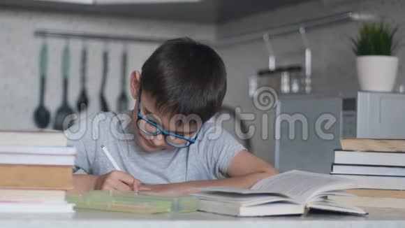 一个男孩用许多教科书和书做家庭作业摄像机向右移动视频的预览图