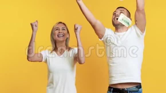 惊喜的幸福夫妇享受着金钱雨中的钞票掉了下来慢动作视频的预览图