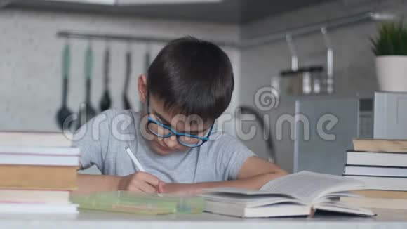 一个男孩用许多教科书和书做家庭作业摄像机移动视频的预览图