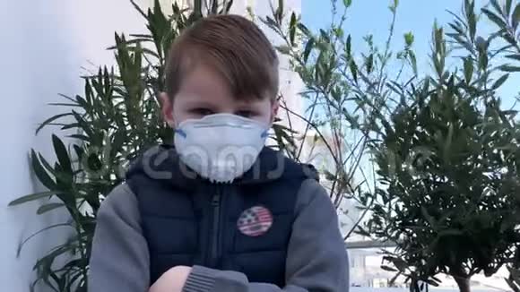 一个戴着面具看镜头的生病孩子感染电晕病毒4K视频的预览图