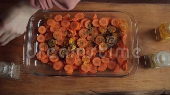 一个年轻的女孩把香料放在一个碗里用切碎的胡萝卜在厨房里做饭特写镜头从上面看视频的预览图