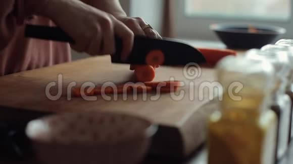 那个女孩在厨房的台面上用一把大刀把胡萝卜切成圆圈特写视频的预览图