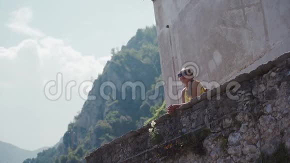 戴墨镜的旅游妇女站在石阶上欣赏小镇景色视频的预览图
