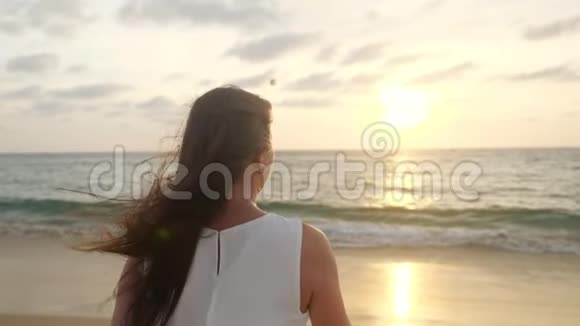 穿着白色衣服的开朗的女士傍晚在海边奔跑视频的预览图