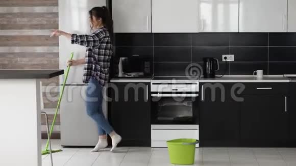 检疫期间厨房里的年轻女子用拖把和舞蹈擦地板在清洁的时候唱歌好好享受吧视频的预览图