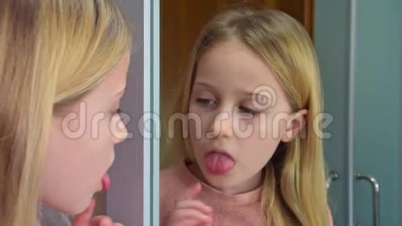 特写漂亮的八岁金发女孩看着她的舌头视频的预览图