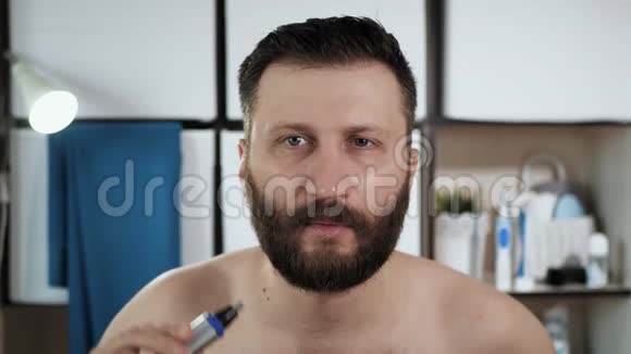 人在耳朵里剪头发年轻有魅力的中年男人在浴室里照镜子用修剪器修剪耳朵视频的预览图