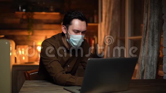 戴着呼吸器的年轻人正在笔记本电脑上打字在家远程工作视频的预览图