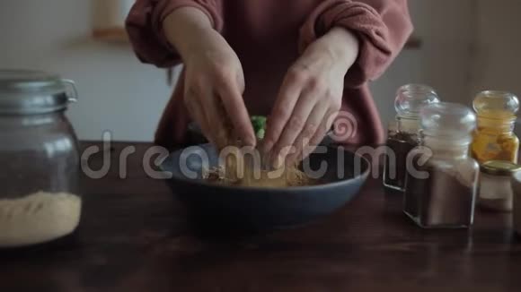 小女孩的特写镜头是用双手在厨房桌子上的一个碗里混合香料在玻璃瓶中混合香料视频的预览图