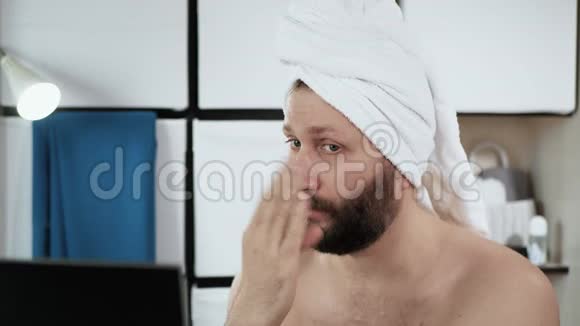 穿着毛巾在浴室里的女人味长胡须的男人在他的头上挥舞双手就像润肤霜一样视频的预览图