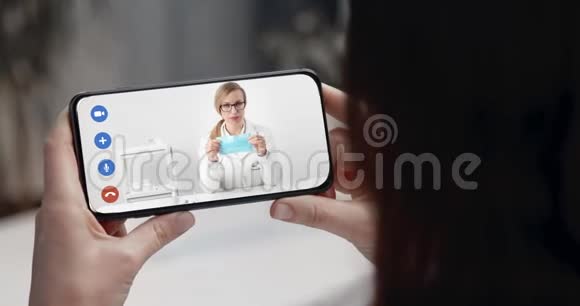 女人在看智能手机上关于防护面罩的视频视频的预览图