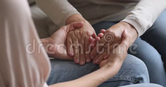 特写年轻女子牵着皱纹的老退休母亲的手视频的预览图