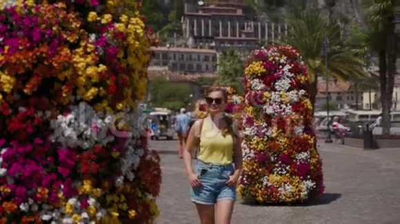 阳光明媚的一天旅游妇女带着彩色的花柱沿着长廊散步视频的预览图