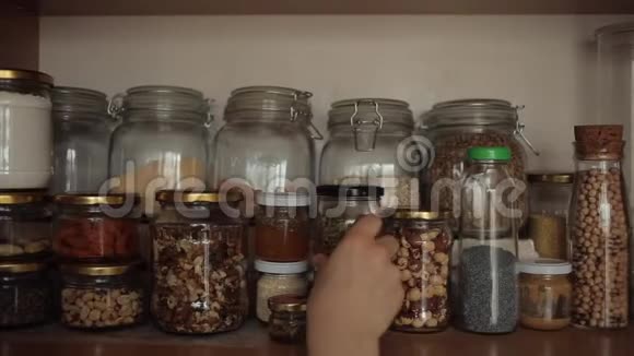 这个女孩在厨房的橱柜里的架子上安排了一些带有凹槽和香料的罐头特写视频的预览图