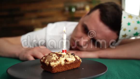 悲伤孤独的年轻人独自庆祝生日坐在生日蛋糕前视频的预览图