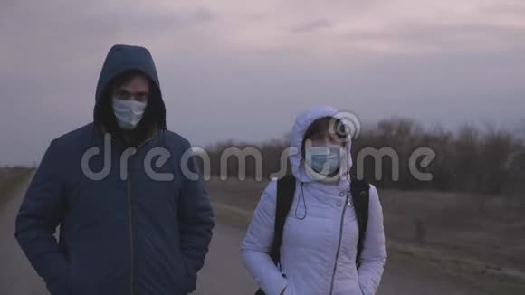 一个女人和一个男人带着一个背包逃离城市戴着防护口罩和帽子沿着城市向外走去视频的预览图