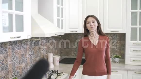 在采访记者时快乐的年轻女子记者带着麦克风采访女孩在家厨房博客视频的预览图