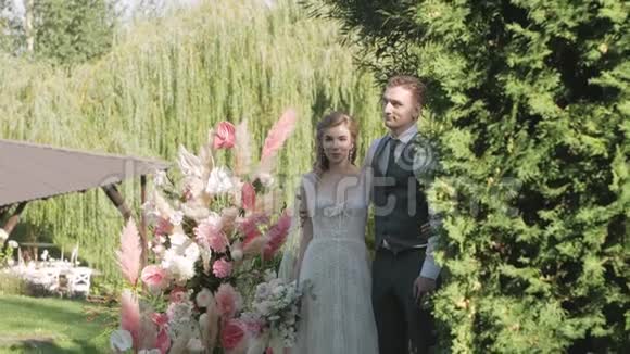 新娘和新郎站在婚礼拱门的背景下微笑视频的预览图