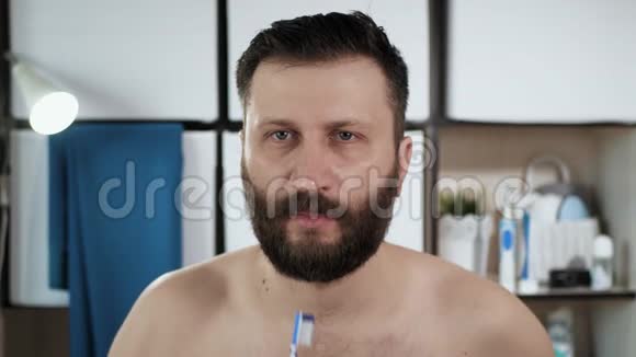 人在刷牙浴室里长着漂亮胡子的男人照镜子用牙刷刷牙视频的预览图