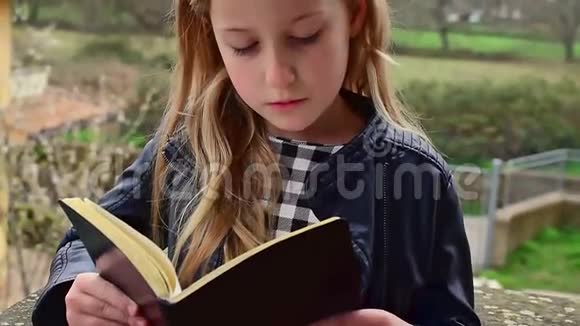 可爱冷静的白种人女孩正在读一本书远程学习视频的预览图