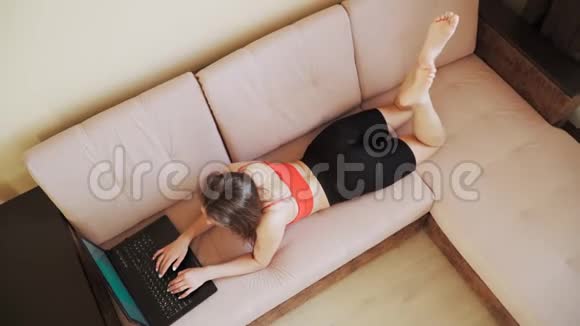 年轻漂亮的自由职业女孩躺在床上在笔记本电脑上工作在家远程工作顶部视图视频的预览图