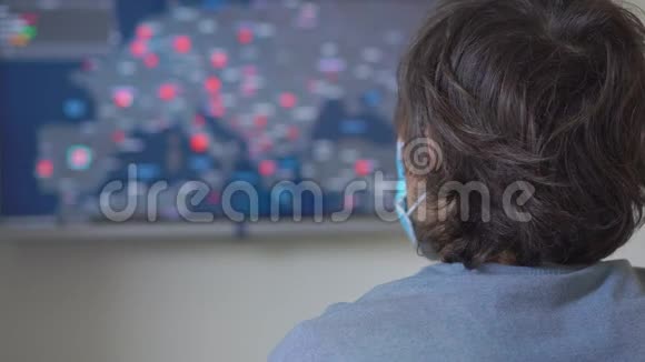一个戴着医用口罩的年轻人看着屏幕屏幕上有多少人感染了covid19视频的预览图