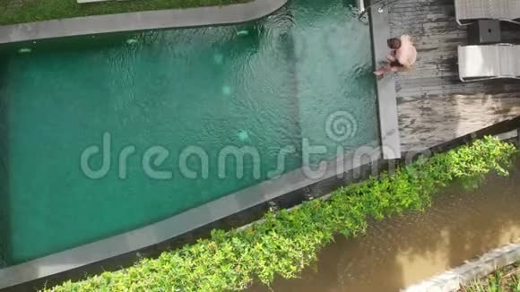 在UbudBali丛林的豪华游泳池里游泳的人的高空俯视图假期概念视频的预览图