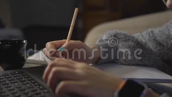 特写十几岁的女孩在笔记本电脑的远程学习前做作业一个用铅笔写字的女孩视频的预览图